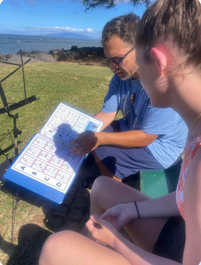 Instructor teaching ukulele technique to student in comfortable studio setting